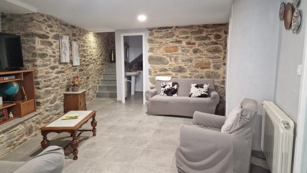 Sala de estar de Casa engracia donde se pueden ver las paredes rústicas de piedra, las escaleras de acceso a la planta superior y el mobiliario, incluidos varios sofás y sillones